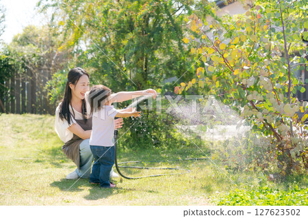 Parents and children watering the garden 127623502