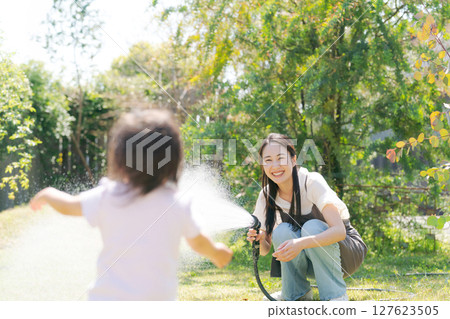 Parents and children watering the garden Parents and children watering the garden 127623505
