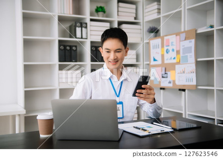 Confident Asian man with a smile standing holding notepad and tablet at the modern office. Confident Asian man with a smile standing holding notepad and tablet at the modern office. 127623546