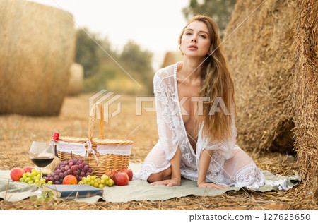 Young woman in negligee kneeling during picnic Young woman in negligee kneeling during picnic 127623650
