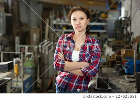 Portrait of confident female worker in workshop of metallurgical plant Portrait of confident female worker in workshop of metallurgical plant 127623651