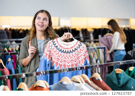 Young woman choosing knitted sweater in store 127623787