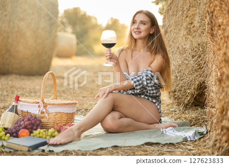 Woman in shirt sitting with wine during picnic 127623833
