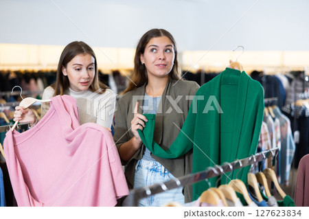 Female friends choosing warm cardigan in store 127623834