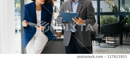 Businesswomen work and discuss their business plans. A Human employee explains and shows her colleague the results paper Businesswomen work and discuss their business plans. A Human employee explains and shows her colleague the results paper 127623953