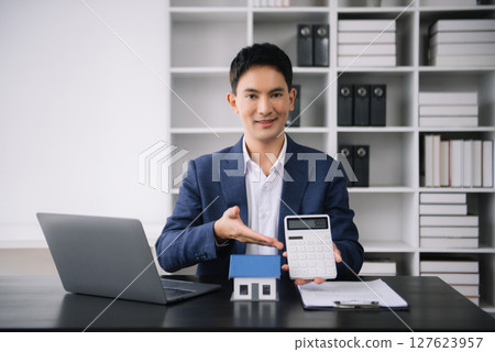 Asian man working with House model real estate agent and customer discussing for contract to buy house, insurance or loan real estate consult concerning mortgage loan offer Asian man working with House model real estate agent and customer discussing for contract to buy house, insurance or loan real estate consult concerning mortgage loan offer 127623957