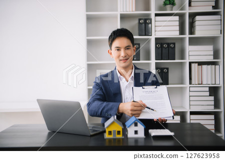 Asian man working with House model real estate agent and customer discussing for contract to buy house, insurance or loan real estate consult concerning mortgage loan offer Asian man working with House model real estate agent and customer discussing for contract to buy house, insurance or loan real estate consult concerning mortgage loan offer 127623958