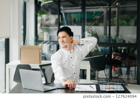 Frustrated young businessman working on a laptop computer sitting at his working place Frustrated young businessman working on a laptop computer sitting at his working place 127624094