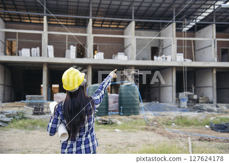 Woman construction engineer hold blueprint wear plaid shirt safety white hard hat at construction site industry labor worker. Architecture Female engineer civil worker look at blueprint real estate Woman construction engineer hold blueprint wear plaid shirt safety white hard hat at construction site industry labor worker. Architecture Female engineer civil worker look at blueprint real estate 127624178