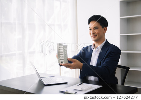 Asian man working with House model real estate agent and customer discussing for contract to buy house, insurance or loan real estate consult concerning mortgage loan offer Asian man working with House model real estate agent and customer discussing for contract to buy house, insurance or loan real estate consult concerning mortgage loan offer 127624277