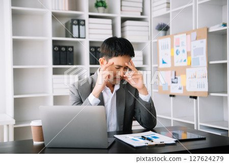 Asian business man is stressed, bored, and overthinking from working on a tablet at the modern office. Asian business man is stressed, bored, and overthinking from working on a tablet at the modern office. 127624279