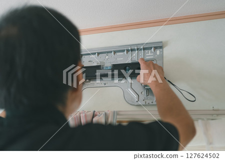 An air conditioner contractor holds a spirit level against the back panel to level the room 127624502