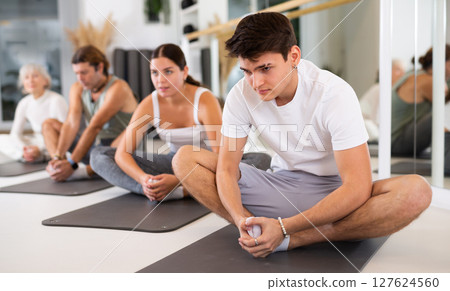 Women and men performing yoga exercises at yoga studio, health concept Women and men performing yoga exercises at yoga studio, health concept 127624560