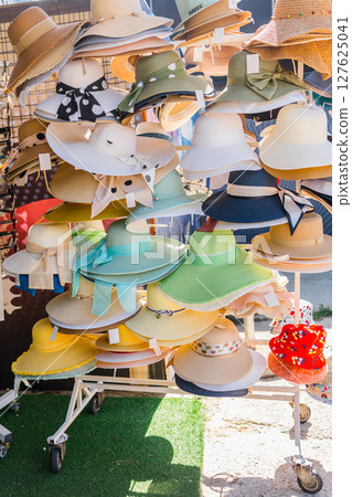 Colorful sun hats on a street market. Fashion accessories, vacation shopping, and summer style inspiration in a coastal town. 127625041