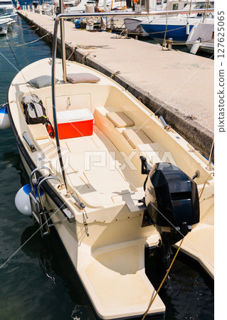 Small motorboats docked in calm marina water. Seaside lifestyle, coastal transportation, and nautical summer atmosphere Small motorboats docked in calm marina water. Seaside lifestyle, coastal transportation, and nautical summer atmosphere 127625065