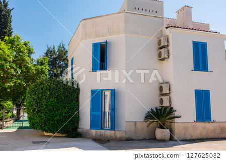 White houses with blue shutters. Mediterranean design, summer climate adaptation, and coastal urban lifestyle with natural elements. White houses with blue shutters. Mediterranean design, summer climate adaptation, and coastal urban lifestyle with natural elements. 127625082