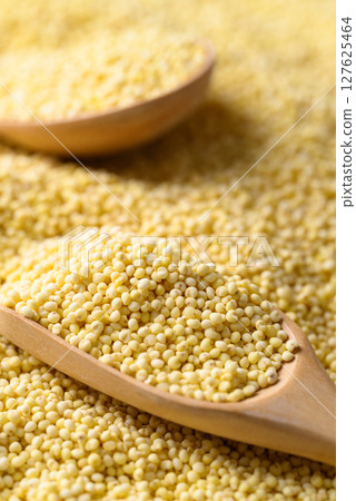 Yellow millet grain in wooden spoon, Food ingredient 127625464