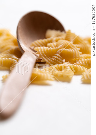 Raw farfalle pasta with wooden spoon on white background, Italian food ingredient 127625504