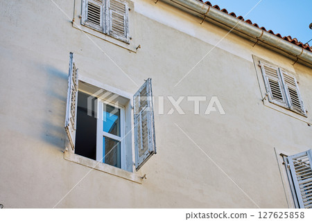Old building facade with open window and wooden shutters 127625858