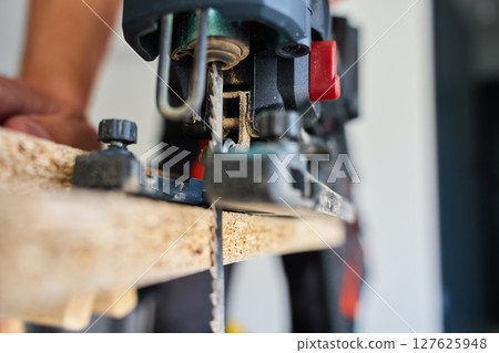 Close-Up of Electric Jigsaw Cutting Wood Panel 127625948