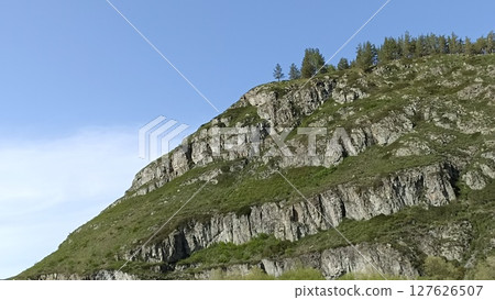 Rocky Mountain Slope with Green Vegetation and a Clear Blue Sky Backdrop. Nature Landscape 127626507
