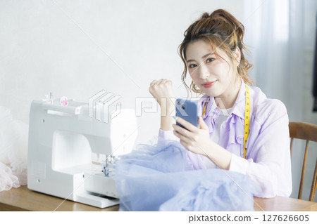 A woman sewing with a sewing machine A woman sewing with a sewing machine 127626605