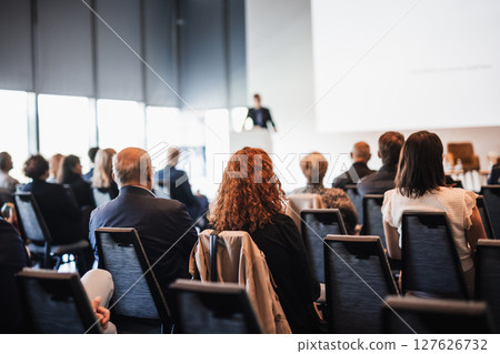 Speaker giving a talk in conference hall at business event. Rear view of unrecognizable people in audience at the conference hall. Business and entrepreneurship concept 127626732