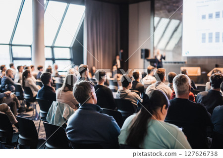 Speaker giving a talk in conference hall at business event. Rear view of unrecognizable people in audience at the conference hall. Business and entrepreneurship concept 127626738