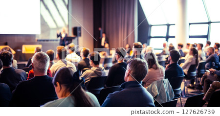 Speaker giving a talk in conference hall at business event. Rear view of unrecognizable people in audience at the conference hall. Business and entrepreneurship concept 127626739