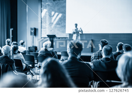 Speaker giving a talk in conference hall at business event. Blue toned black and white image 127626745