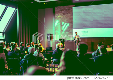 Speaker giving a talk in conference hall at business event. Rear view of unrecognizable people in audience at the conference hall. Business and entrepreneurship concept 127626762