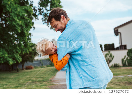 Father playing with toddler son, holding him upside down. Father playing with toddler son, holding him upside down. 127627072