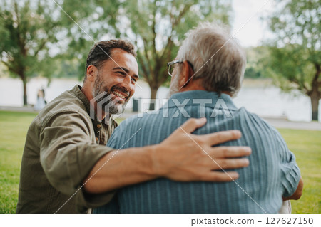Happy dad and adult son enjoying peaceful afternoon outdoors 127627150
