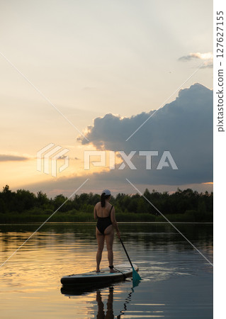 Paddleboarding at Sunset on a Tranquil Lake 127627155