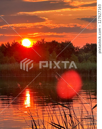 Serene Sunset Reflection Over a Tranquil Lake Serene Sunset Reflection Over a Tranquil Lake 127627163