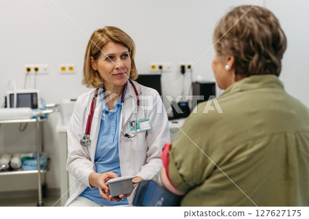 Elderly female patient undergoing blood pressure test at routine check-up. 127627175