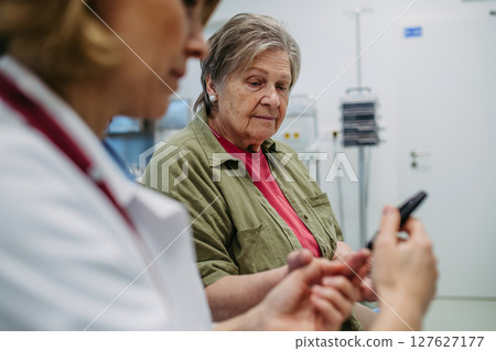 Female doctor using blood glucose meter during medical exam. 127627177