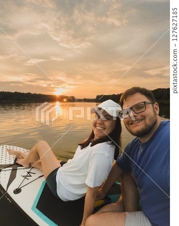 Couple Paddleboarding at Sunset 127627185