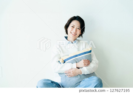 Young woman sitting in front of a wall Young woman sitting in front of a wall 127627195