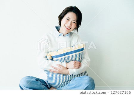 Young woman sitting in front of a wall Young woman sitting in front of a wall 127627196