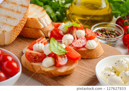 Bruschetta with cherry tomatoes and mozzarella on wooden board. 127627833