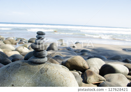 Zen Stone Balance or large stone at Rocky Beach as a support with a background of sea waves 127628421