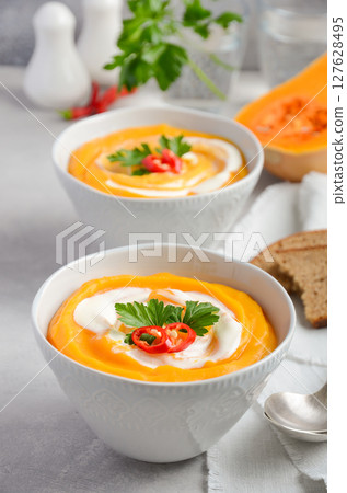 Pumpkin soup with cream and parsley on a grey concrete or stone background, selective focus 127628495