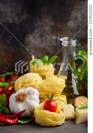 Pasta, vegetables, herbs and spices for Italian food on the wooden background, selective focus, copy space. 127628501