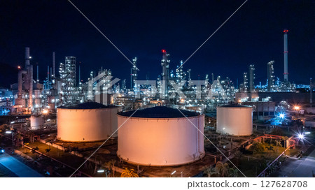 Oil refinery petrochemical plant at dusk illuminated storage tank industrial infrastructure, Oil refinery petrochemical product storage tank at oil refinery factory industry, Global energy refinery. Oil refinery petrochemical plant at dusk illuminated storage tank industrial infrastructure, Oil refinery petrochemical product storage tank at oil refinery factory industry, Global energy refinery. 127628708