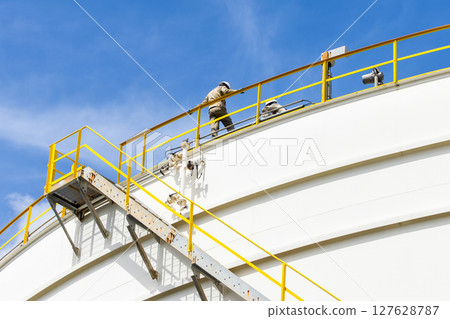 Industrial engineer work on top of crude oil storage tank, Two male worker inspection on the top of oil storage tank inspection visual check oil storage tank. 127628787