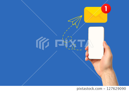 A hand is displaying a smartphone with a notification indicating a new message A hand is displaying a smartphone with a notification indicating a new message 127629090