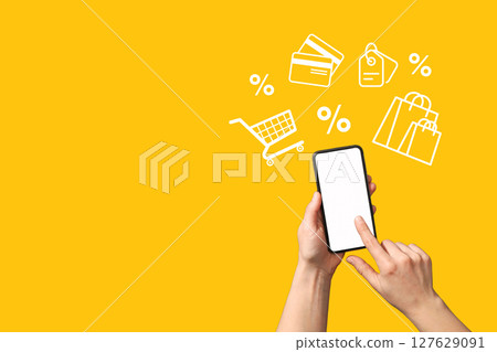 A user shops online on a smartphone against a bright yellow background 127629091