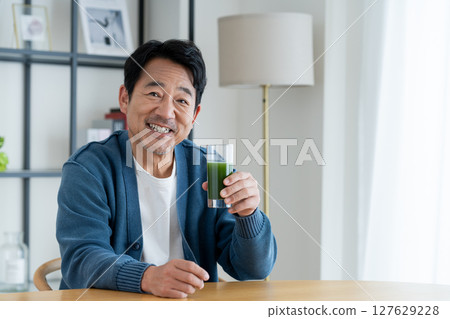 Middle-aged man drinking green juice at home Middle-aged man drinking green juice at home 127629228