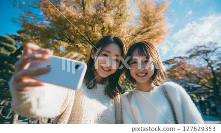 Women taking selfies with autumn leaves 127629353